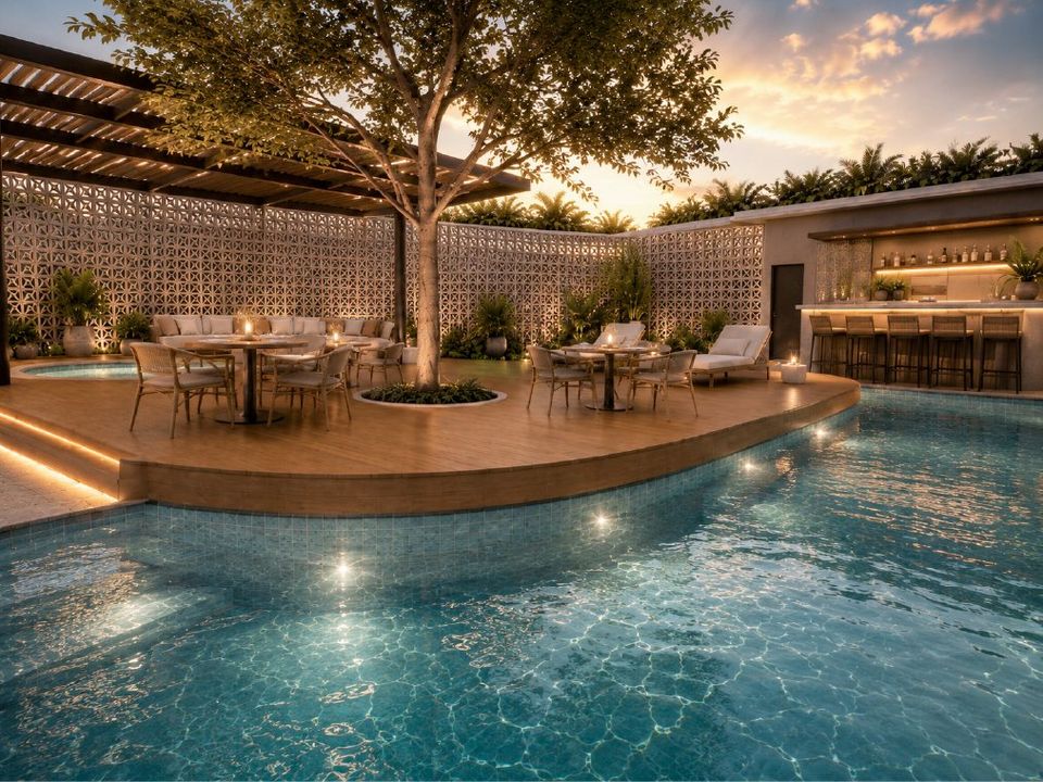 Patio de la piscina al anochecer, con el árbol al centro y mesas junto al agua